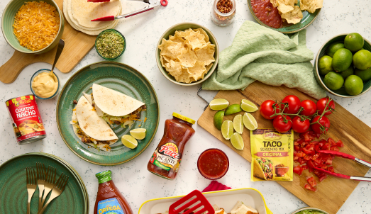 Hispanic-inspired meal spread — tacos, tortilla chips, salsa, limes, cheese and taco seasoning