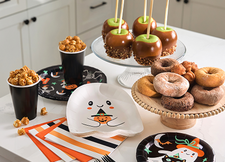 Halloween party table with caramel apples, donuts, ghost plate and festive tableware